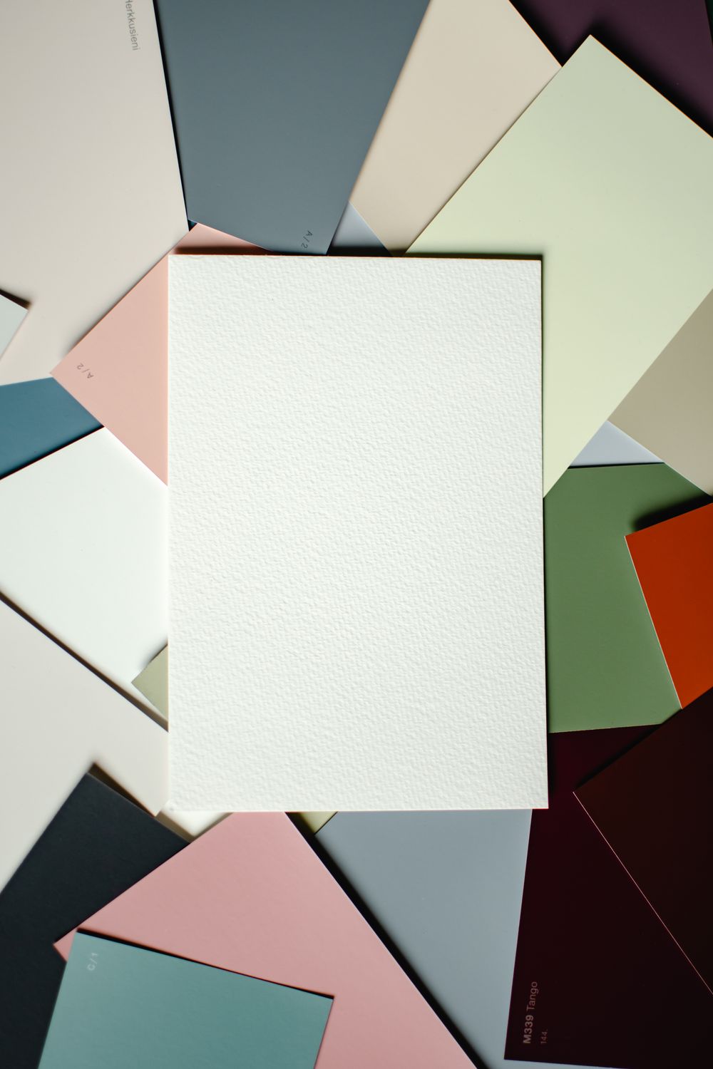 A blank textured white card laid over overlapping muted color swatches.